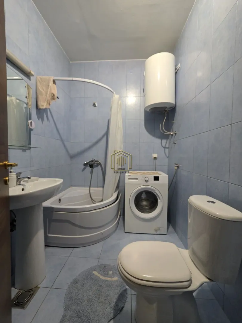 Kupatilo obloženo pločicama sa kadom, umivaonikom, WC šoljom i mašinom za veš.