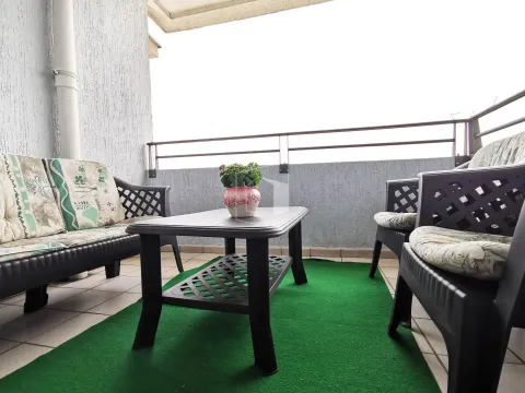 A balcony with outdoor seating and a green rug. - image 16
