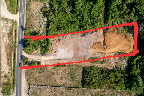 Pogled iz vazduha na građevinsku parcelu sa označenim granicama pored puta. - image 5