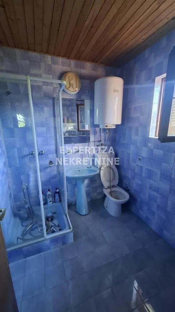 Smaller bathroom with blue tiles, a shower cabin, and sanitary fixtures.