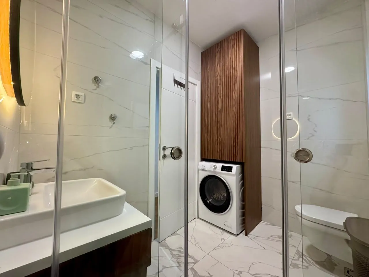 Modern bathroom with sink, toilet, and washing machine.