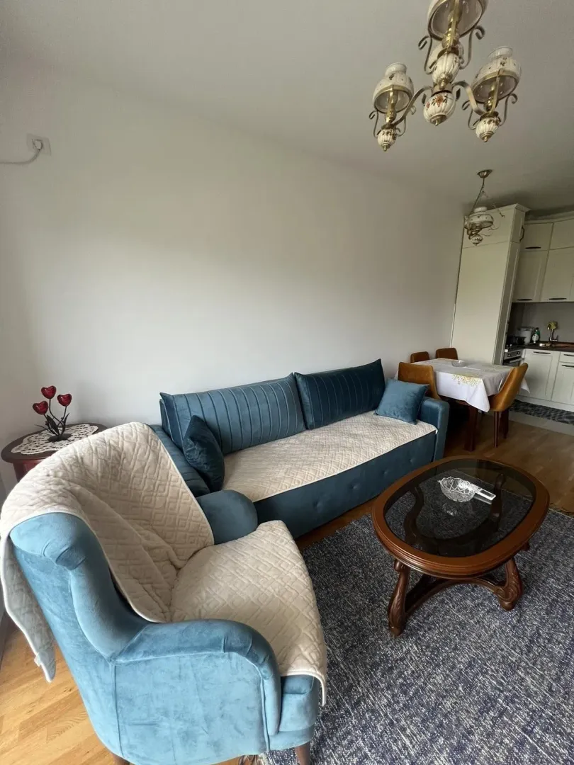 Living room with blue seating area and dining space in the background.