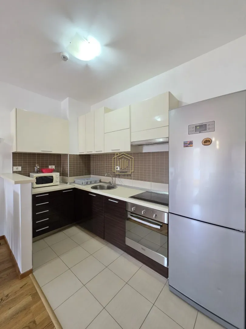 Kitchen with white upper cabinets, dark lower cabinets, and a refrigerator.