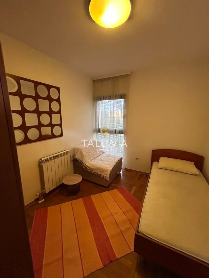Smaller bedroom with a bed, an armchair, and a decorative wall panel.