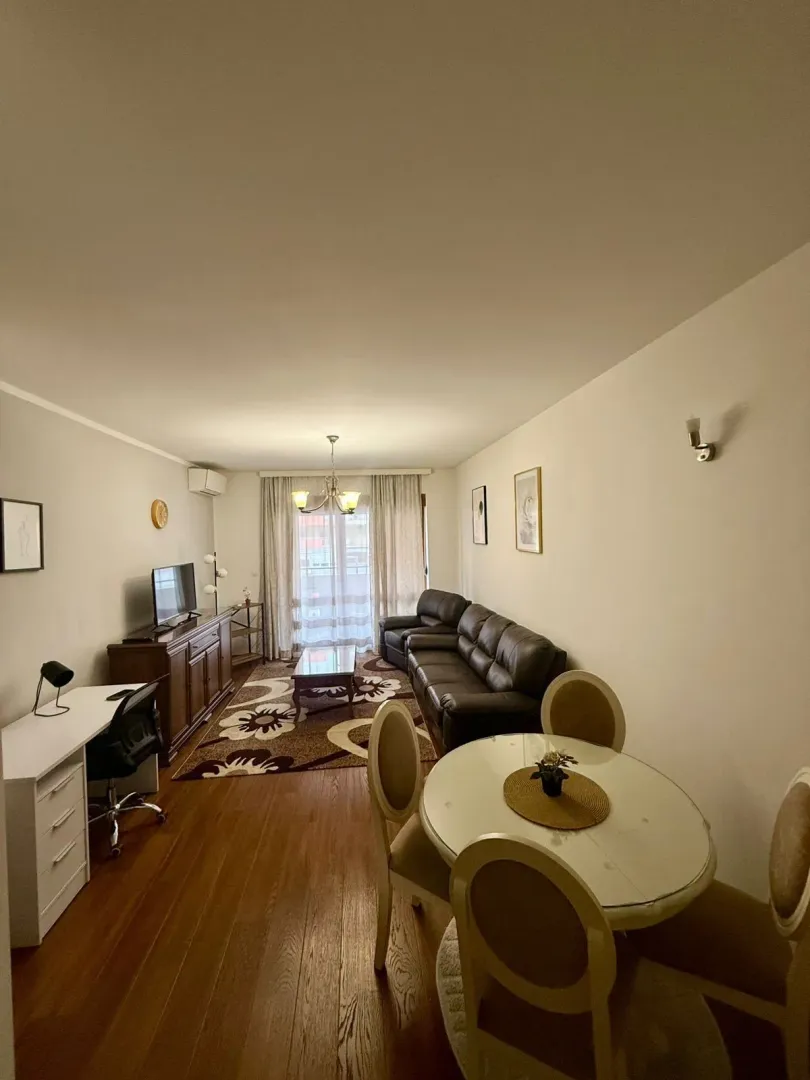 Bright living room with a leather sofa, dining table, and a small study desk.