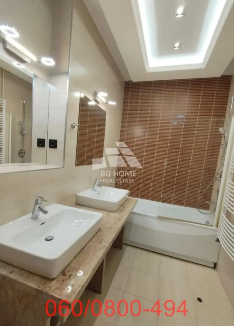 Modern bathroom with double sinks, a bathtub and a large mirror.