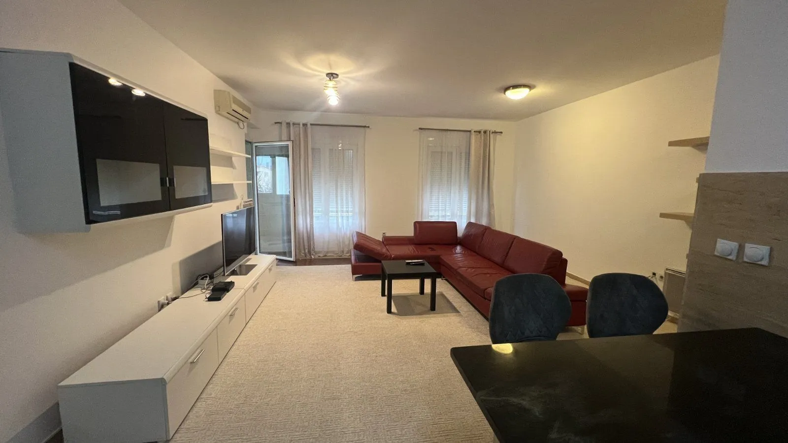 Bright living room featuring a red sectional sofa and a TV console.