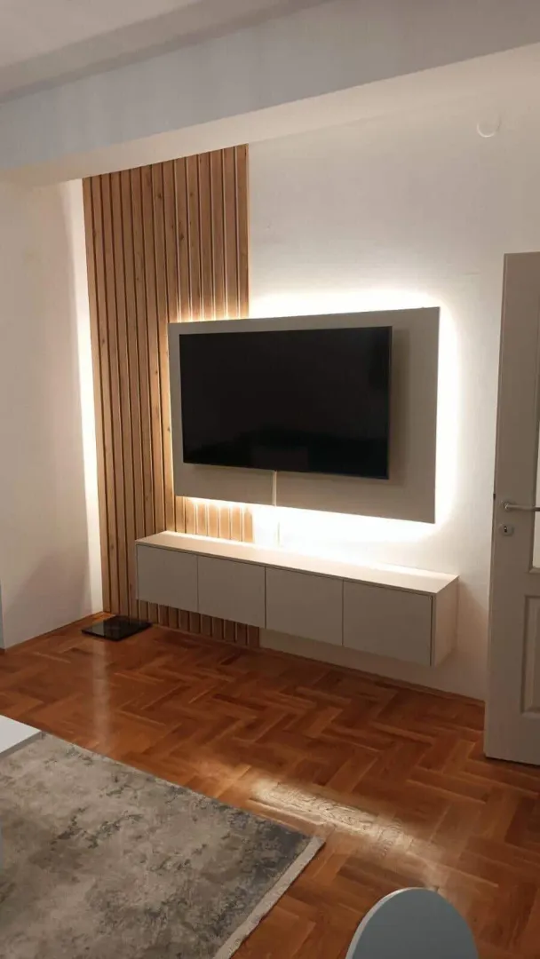 Dnevna soba sa TV policom, drvenim zidnim panelima i parketom.
