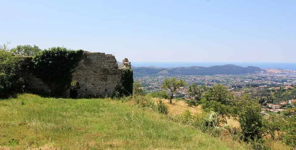Stara kamena ruševina na uzvišenju sa pogledom na grad i more.