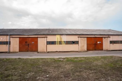 Exterior view of a single-story industrial building with large metal doors. - image 2