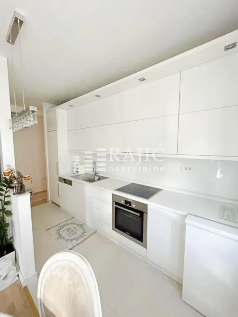 Modern white kitchen with built-in appliances and white countertops.