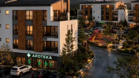 Pogled na moderno stambeno-poslovni kompleks u sumraku sa apotekom u prizemlju i uređenim dvorištem. - image 7