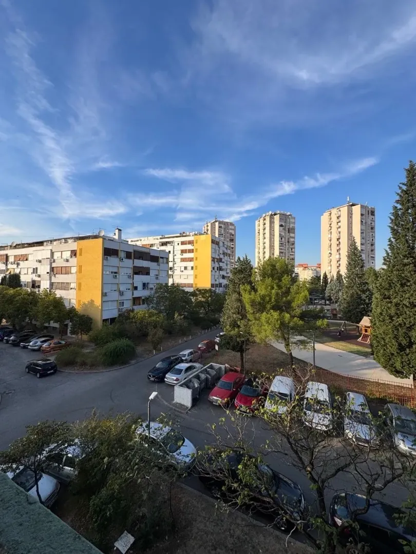 Pogled sa terase na okolne stambene zgrade i parking.