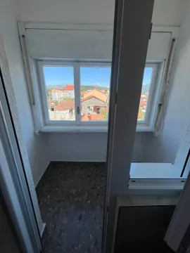 View through the window from the terrace towards surrounding buildings and hills. - image 5