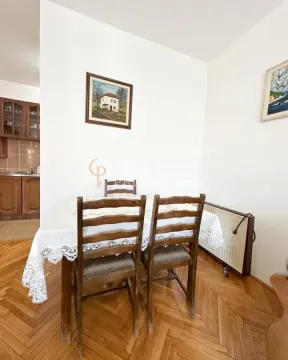 Trpezarija sa drvenim stolom i stolicama, sa pogledom na dio kuhinje. - image 2