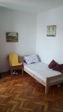 Manja spavaća soba sa krevetom, drvenom foteljom i parketom. - image 4