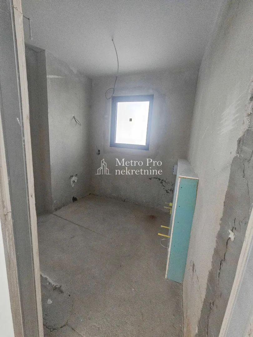 Prazna prostorija u sivoj fazi gradnje sa prozorom.