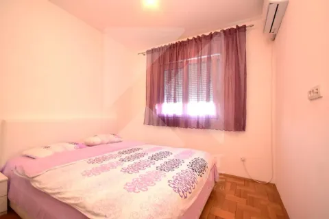 Spavaća soba sa bračnim krevetom i prozorom sa ljubičastim zavesama. - image 7
