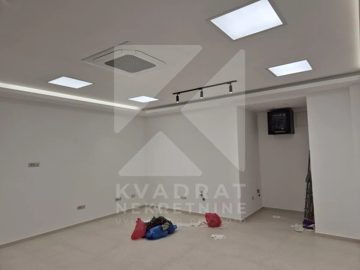 An empty room with a drop ceiling, built-in lighting, and an air conditioning unit.