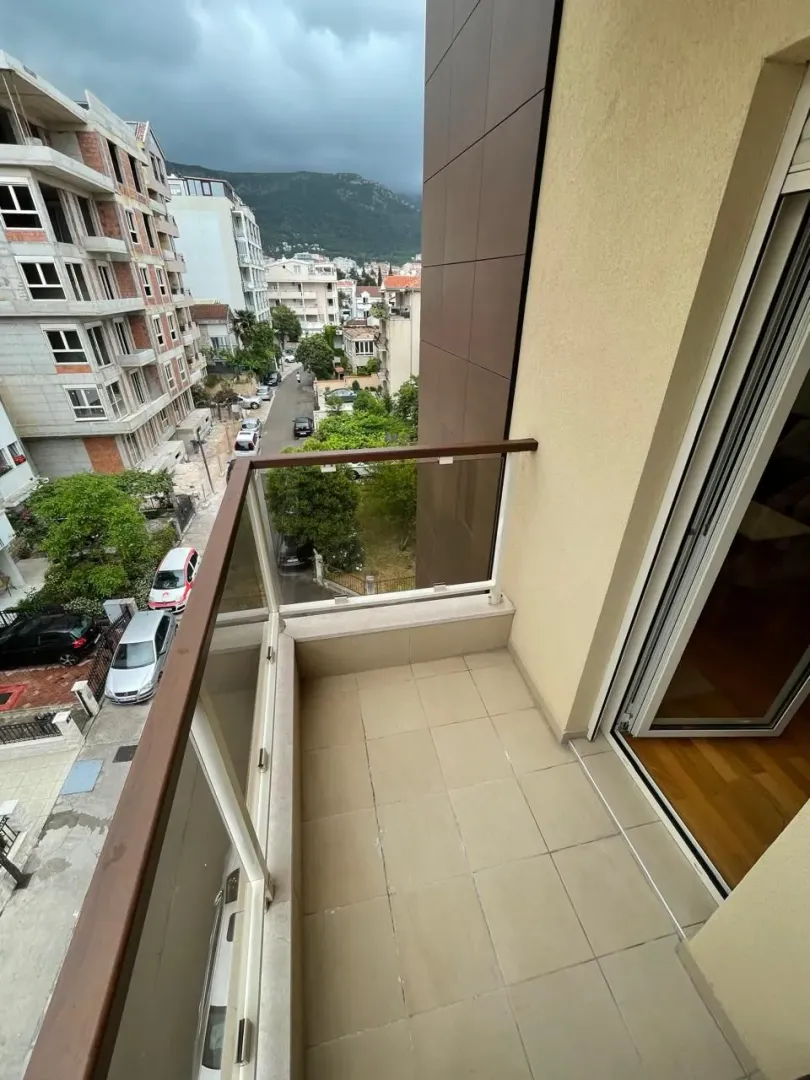 Manji popločani balkon sa staklenom ogradom i pogledom na ulicu.