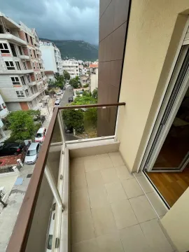 Manji popločani balkon sa staklenom ogradom i pogledom na ulicu. - image 12