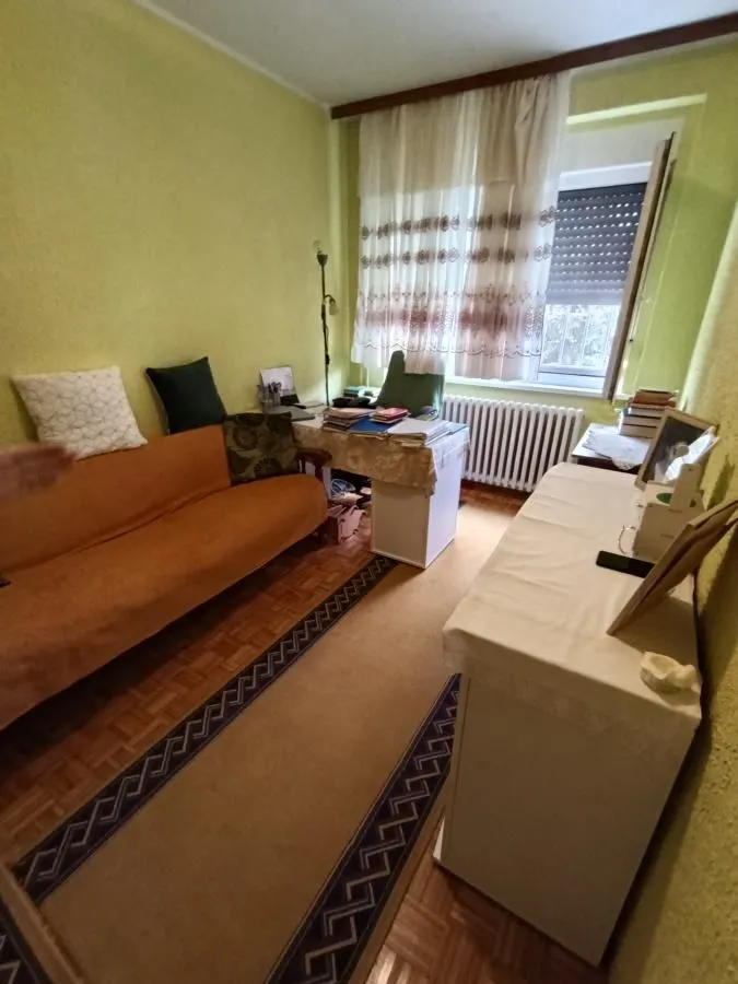 Dnevna soba sa kaučem, radnim stolom i prozorom.