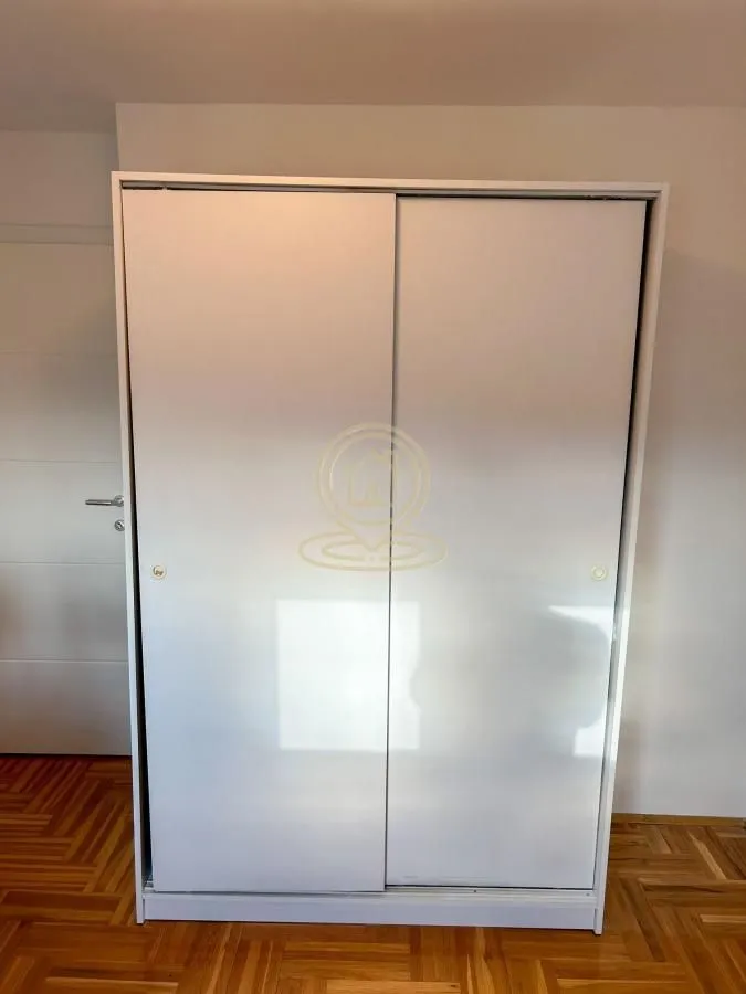 Beli garderober sa kliznim vratima u sobi.