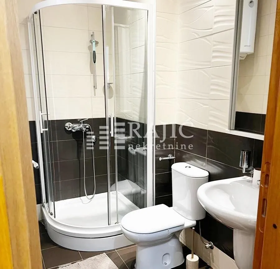 Small bathroom with a shower cabin, washbasin, and toilet.