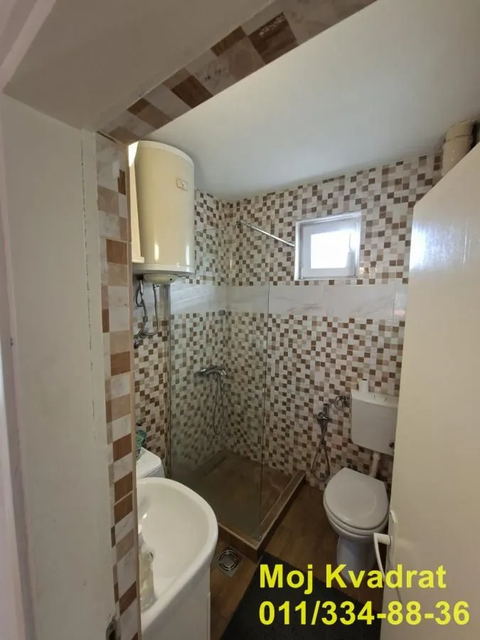 Small tiled bathroom equipped with a walk-in shower and water heater.