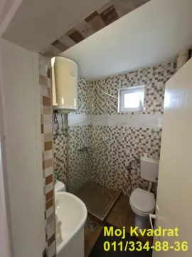 Small tiled bathroom equipped with a walk-in shower and water heater. - image 13