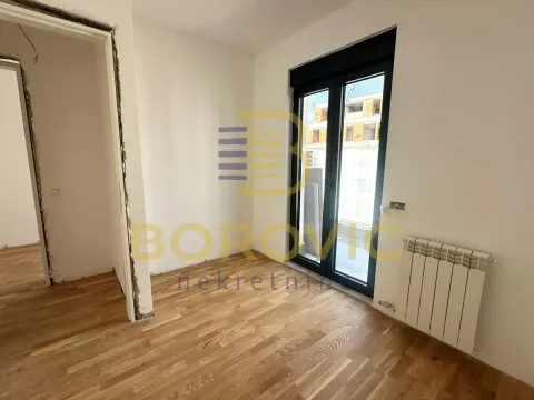 Prazna soba sa parketom, belim zidovima i balkonskim vratima. - image 3