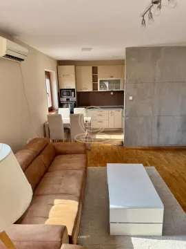 Living room with a sofa and a view towards the dining area and kitchen in the background. - image 5
