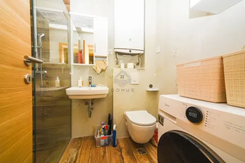 Small bathroom with a shower cabin, washbasin, toilet, and washing machine. - image 9