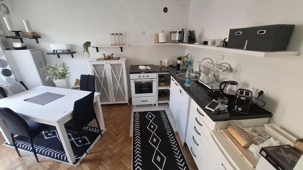 Kuhinja sa trpezarijom i belim elementima.