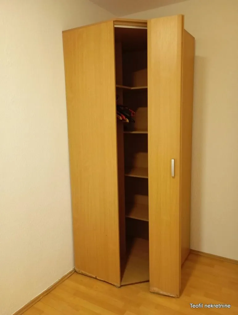 Wooden wardrobe in the corner of the room with shelves inside.