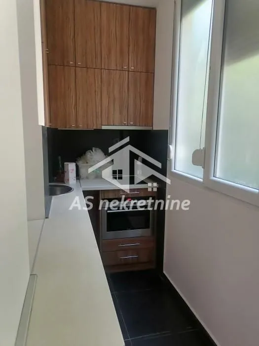 Manja kuhinja sa drvenim elementima i ugrađenim aparatima.