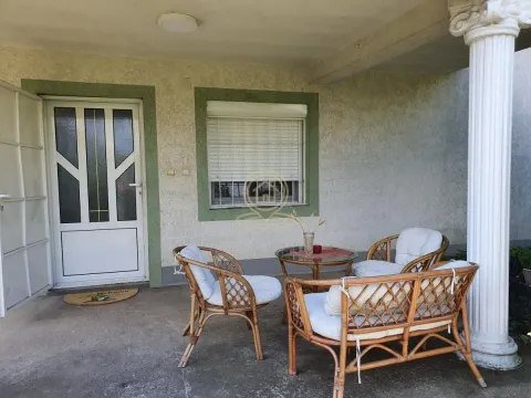 Natkrivena terasa sa garniturom za sedenje od pruća i belim stubom. - image 17