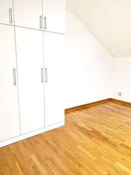 Bright bedroom with a fitted wardrobe and wooden flooring. - image 11