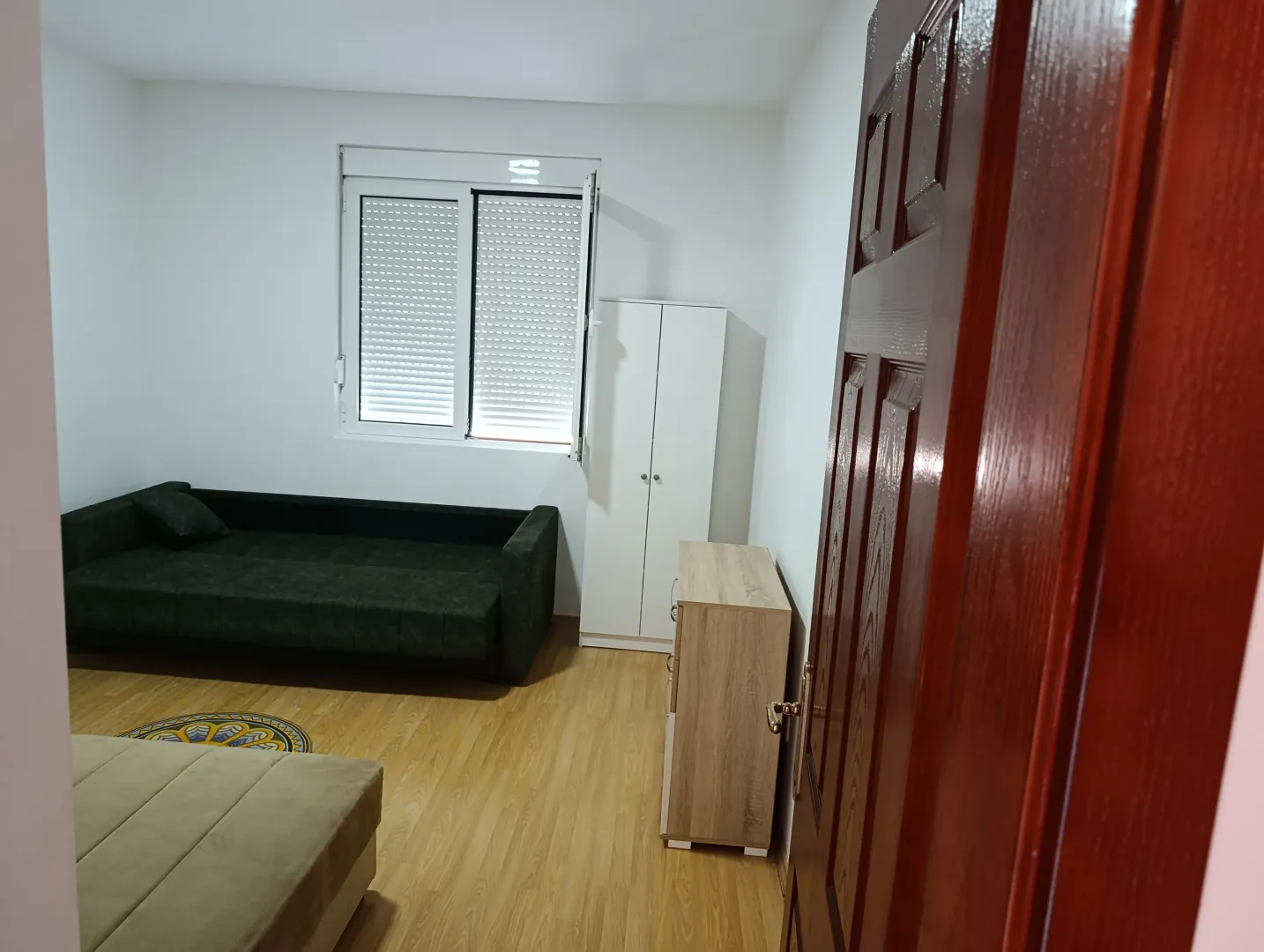 Small living room with a sofa, window, and wooden flooring.