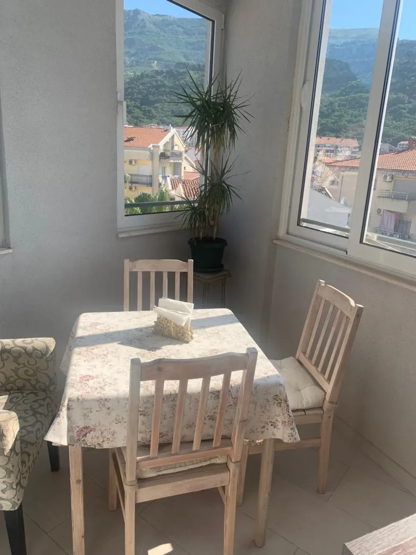Zastakljena terasa sa trpezarijskim stolom i pogledom na grad i planine.