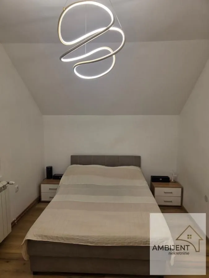 Furnished bedroom with a double bed and a modern chandelier.