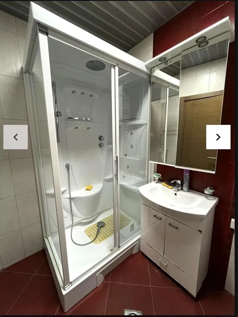 Bathroom equipped with a hydromassage shower cabin and a vanity unit with a washbasin.