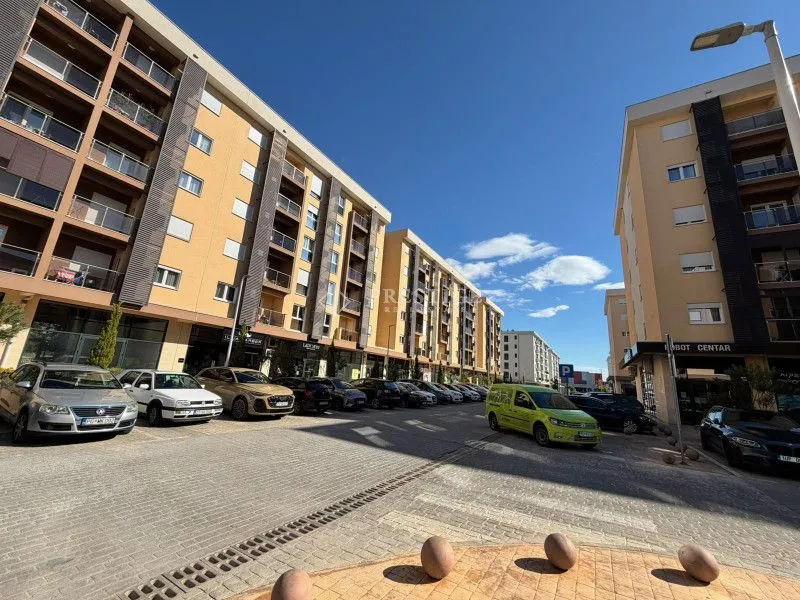 Exterior of residential buildings with a paved courtyard and parked cars.
