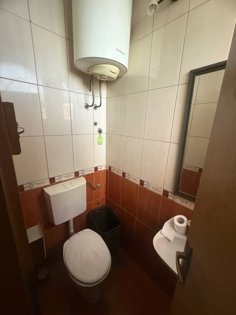 Small bathroom with a toilet, washbasin, water heater, and two-tone wall tiles.