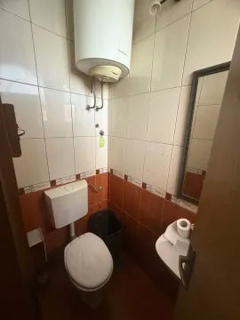 Small bathroom with a toilet, washbasin, water heater, and two-tone wall tiles. - image 5