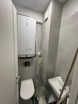 Small bathroom with a toilet, sink, and water heater on the wall. - image 17