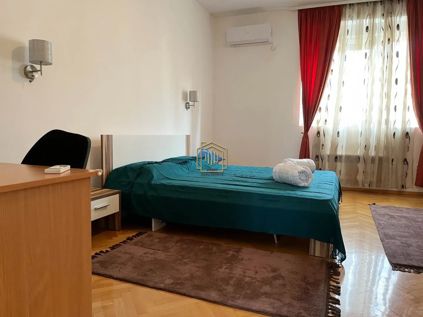 Spavaća soba sa bračnim krevetom, radnim stolom i prozorom sa zavjesama.