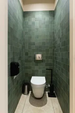 Small bathroom tiled in green with a toilet. - image 17