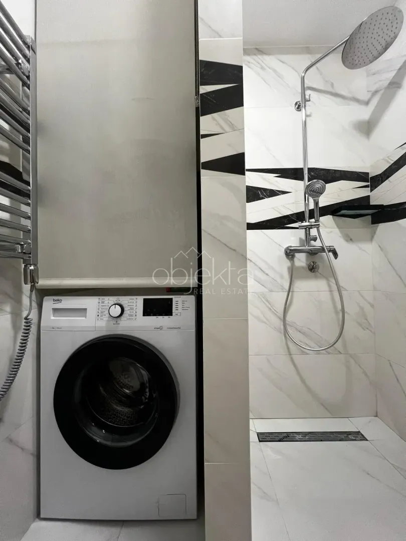 Moderne kupatilo sa tuš kabinom i veš mašinom.