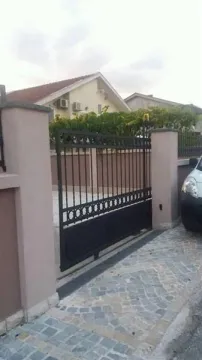 Metal gate at the entrance of a house courtyard with a paved driveway. - image 4